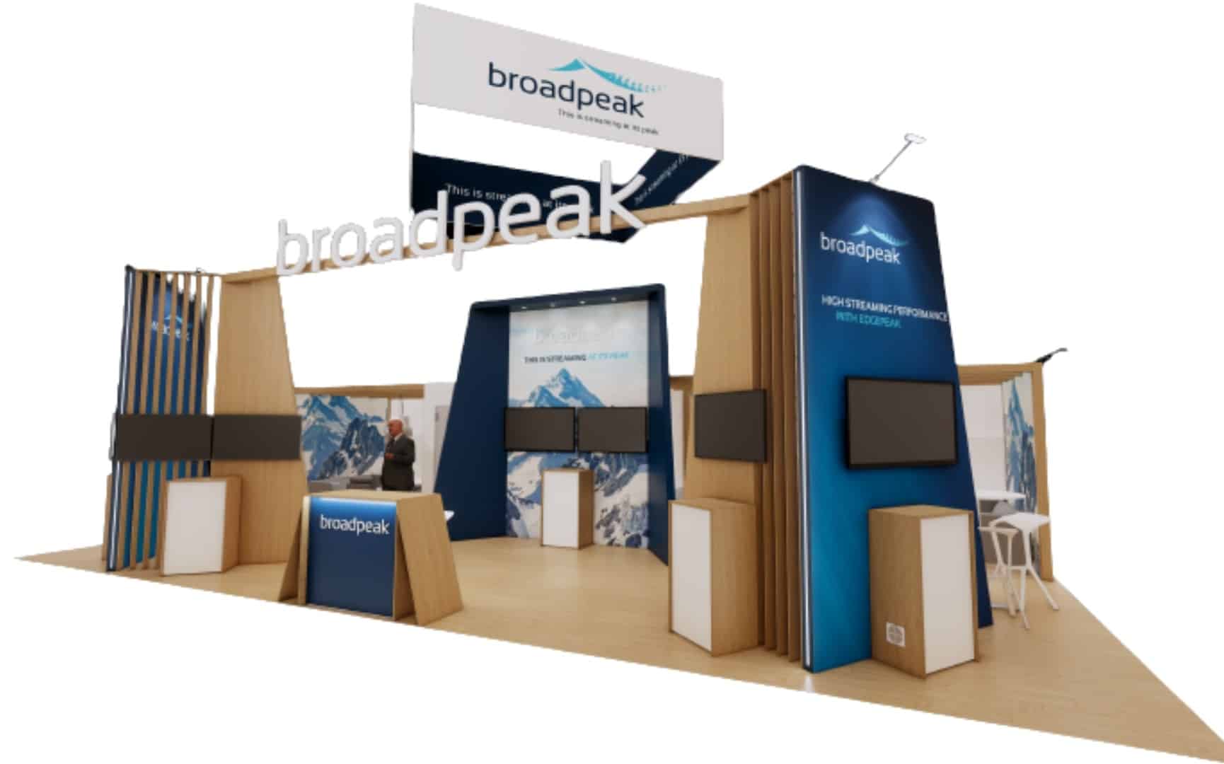 3D rendering of the Broadpeak booth at NAB Show 2026 featuring large overhead Broadpeak branding, blue and wood design elements, multiple video demo screens, and presentation areas for showcasing streaming and CDN technologies.